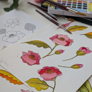 art supplies and painted florals and sketches of unpainted flowers